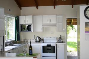 una cocina con electrodomésticos blancos y un reloj en la pared en Ohuka Lodge, en Tuai