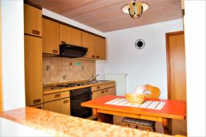 uma cozinha com armários de madeira e uma mesa vermelha em 1 Bergpanorama und atemberaubende alpine Almlandschaft -Nichtraucherdomizil em Schönau am Königssee
