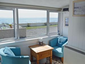 a living room with two chairs and a table and windows at Seascape in Balintore