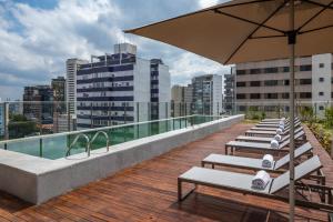 a row of lounge chairs on the roof of a building at Noon Vila Madalena in São Paulo