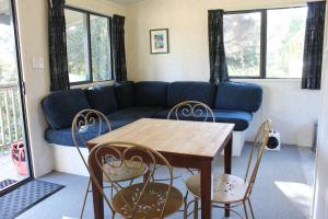 - un salon avec un canapé, une table et des chaises dans l'établissement Russell-Orongo Bay Holiday Park, à Russell