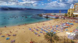 une plage avec beaucoup de gens dans l'eau dans l'établissement Bohemian Loft - Las Canteras Beach, à Las Palmas de Gran Canaria