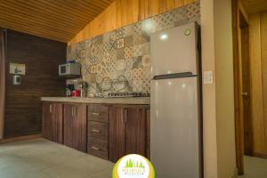 a kitchen with a refrigerator and wooden cabinets at Cabaña La Mazatleca en Mexiquillo in La Ciudad