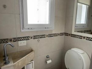baño con aseo y lavabo y ventana en Estudio en Belén de Escobar
