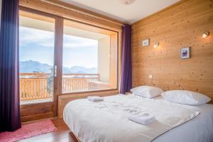 een slaapkamer met een bed en een groot raam bij Superb apartment with balcony in the heart of Huez - Welkeys in Huez