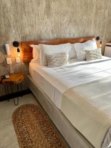 uma cama grande com lençóis brancos e almofadas num quarto em Casa Valentini Pousada em Jericoacoara
