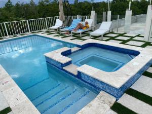 una persona sentada en una silla junto a una piscina en Joy Estate Rooftop Pool n View unit #1, en Falmouth