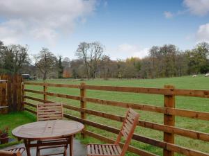 a wooden table and chairs next to a fence at Seventeen Ten in Castle Carrock