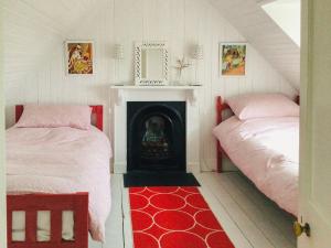 a bedroom with two beds and a fireplace with a mirror at Owl Cottage in Kilmote
