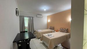 a room with two beds and a desk and a window at HOTEL UNA in Palmares