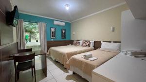 um quarto com 2 camas, uma secretária e uma mesa em HOTEL UNA em Palmares