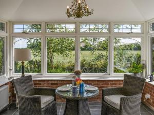 a living room with a table and chairs and windows at Hoggets Nest in Bedingfield