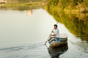 a man is rowing a boat in the water at Solar Mirador Exclusive Resort e SPA in Praia do Rosa