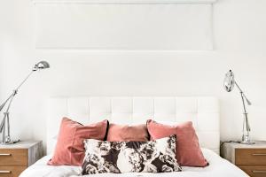 a white bedroom with pink pillows on a bed at Rooftop Condo in Nashville