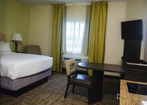 Candlewood Suites Houston Medical Center, an IHG Hotel في هيوستن: غرفة في الفندق بسرير ومكتب وطاولة