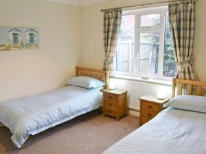 two twin beds in a room with a window at Southbank in Mundesley