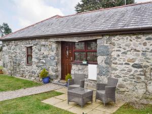 una casa de campo de piedra con sillas frente a ella en Bwthyn Clyd, en Dyffryn