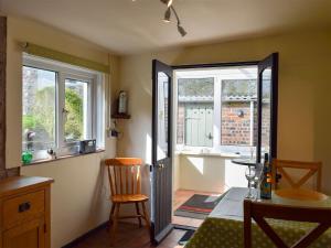 a room with a table and a chair and windows at Augustus Cottage in Rowlstone