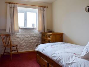 a bedroom with a bed and a chair and a window at Augustus Cottage in Rowlstone