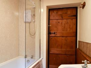 baño con puerta de madera, bañera y lavamanos en Augustus Cottage en Rowlstone