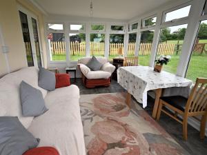 sala de estar con sofás, mesa y ventanas en Orchard Farm Cottage, en Barnby