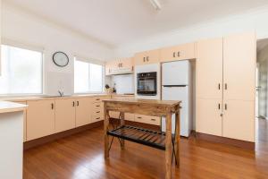 a kitchen with white cabinets and a wooden table at Cottage on Bruce in Forster