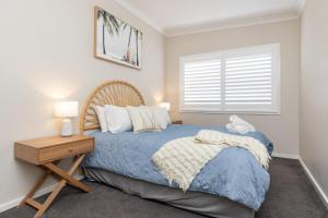 a bedroom with a bed with a nightstand and a window at Cottage on Bruce in Forster