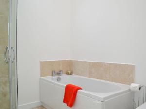 a bathroom with a bath tub with a red towel on it at Wester Laggan Cottage in Skye of Curr