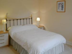 1 dormitorio con 1 cama con sábanas blancas y 2 lámparas en Lukesland Farm en Harford