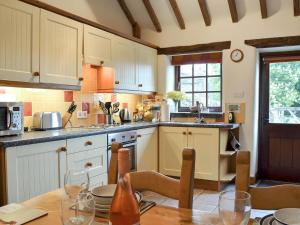 een keuken met witte kasten en een houten tafel bij Spring Cottage in Hollinsclough