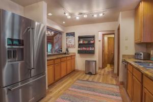 a kitchen with a stainless steel refrigerator and wooden cabinets at Aspencliffe Home: Perfect Mountain Getaway w/ Hot Tub in Blue River