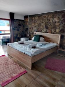 1 dormitorio con cama de madera y pared de piedra en Casa David, en Sviniţa