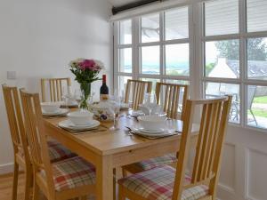 mesa de comedor con sillas y mesa con copas de vino en Wester Laggan Cottage en Skye of Curr
