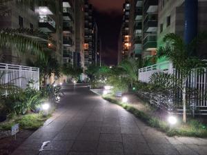 a walkway in a city at night with lights at Apartamento na praia de Jatiúca com piscina e área de lazer in Maceió