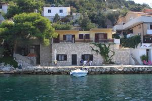 a small boat in the water in front of a house at Apartments by the sea Zaklopatica, Lastovo - 8347 in Lastovo