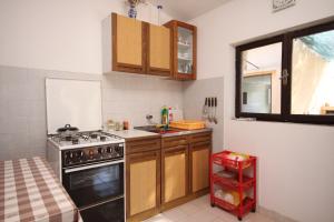 a small kitchen with a stove and a sink at Secluded fisherman's cottage Lavdara, Dugi otok - 8155 in Sali
