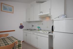 a white kitchen with a sink and a refrigerator at Apartments by the sea Nerezine, Losinj - 3479 in Nerezine