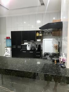 cocina con encimera negra y nevera en Casa Vitória, en Camocim