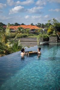 dwóch mężczyzn w basenie w wodzie w obiekcie Royal Roco Villa w mieście Tanah Lot
