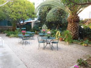 a patio with tables and chairs and a palm tree at Hotel Villa Les Cygnes in Nice