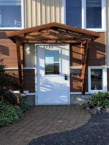 a house with a white door with a wooden roof at Aux quatre vents 4,5 grand logement privé in Lac-Mégantic