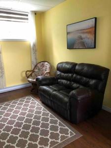 a living room with a leather couch and a chair at Aux quatre vents 4,5 grand logement privé in Lac-Mégantic