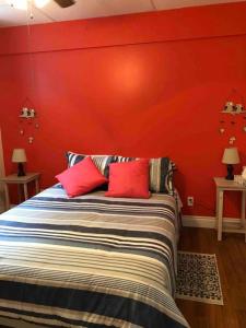 um quarto com uma parede vermelha e uma cama com almofadas vermelhas em Aux quatre vents 4,5 grand logement privé em Lac-Mégantic