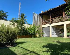 a house with a green yard with a building at Casa Fogo in Itaúnas