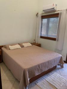 a bedroom with a bed and a window with a heater at Casa Fogo in Itaúnas