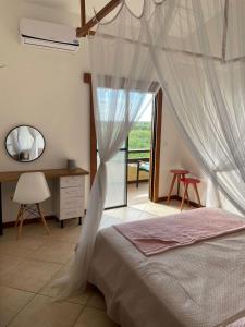 a bedroom with a bed with a mosquito net at Casa Fogo in Itaúnas