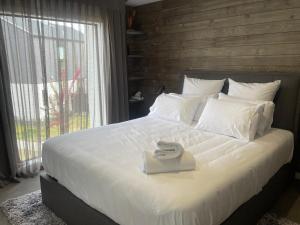 a bedroom with a large white bed with a large window at Alpine Junction Townhouse Apartments, Lodge & Hotel in Wanaka