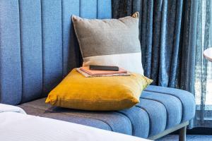 a remote control sitting on a pillow on a blue couch at voco Melbourne Central in Melbourne