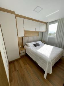 a bedroom with a white bed and a window at Apartamento completo para veraneio in Torres
