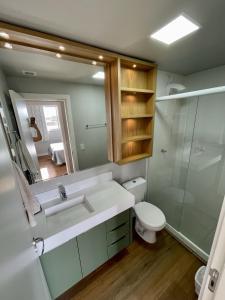 a bathroom with a sink and a toilet and a mirror at Apartamento completo para veraneio in Torres